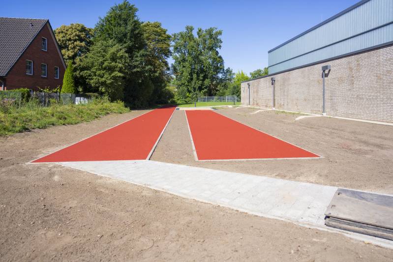 Hochwertige Laufbahn für Sportler: Die Laufbahn und Anlaufbahn aus strapazierfähigem Kunststoff, entwickelt von Boymann im Garten- und Landschaftsbau, bieten hohe Qualitätsstandards und eine Sandsprunggrube für zusätzliche sportliche Herausforderungen.